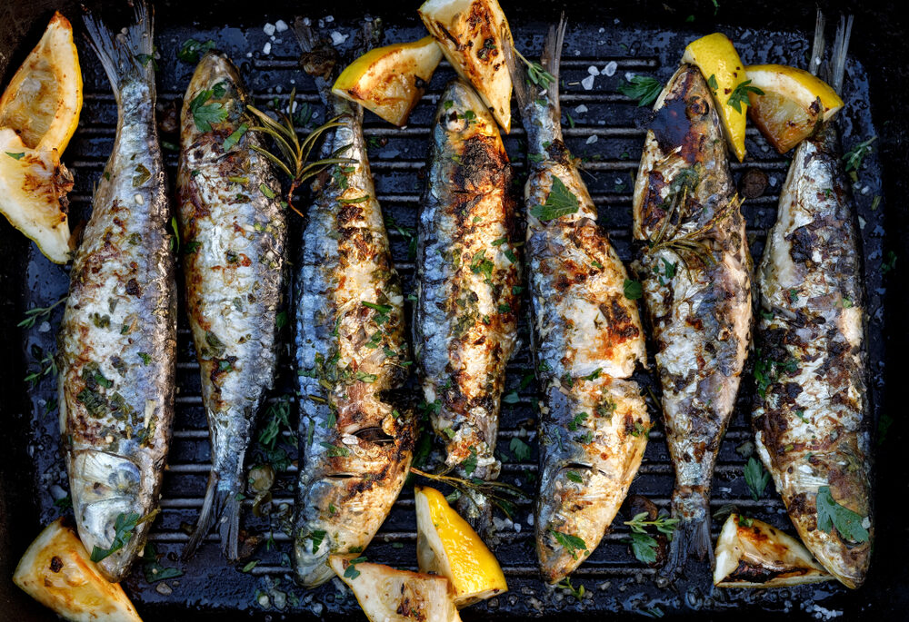Overhead view of grilled sardines and lemons.