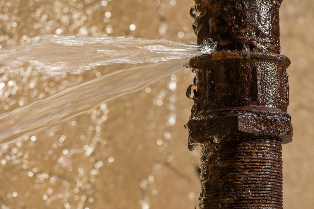 Rusty burst pipe spraying water