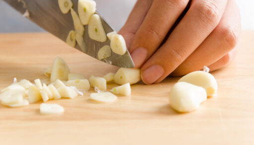 Close-up of a person's hands while they are chopping garlic.