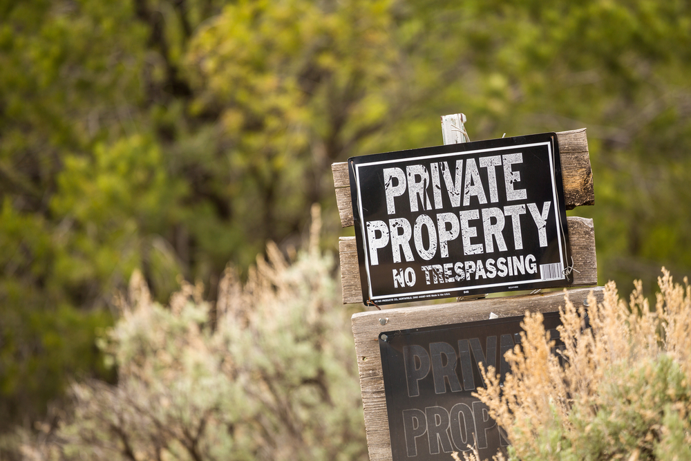 Private property and no trespassing sign in a field.