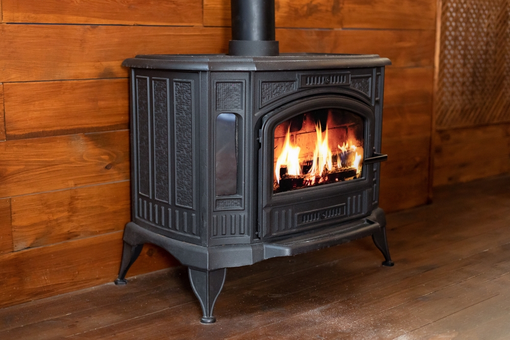 Close-up of a wood-burning stove in a room with wood panelling.