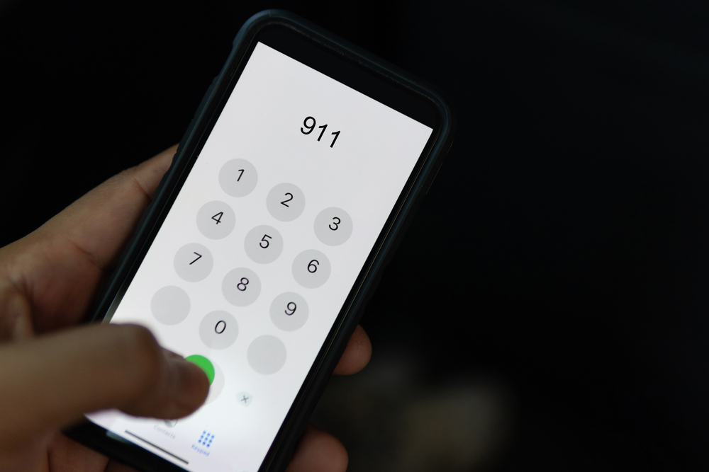 Person holding a phone and dialling 911.