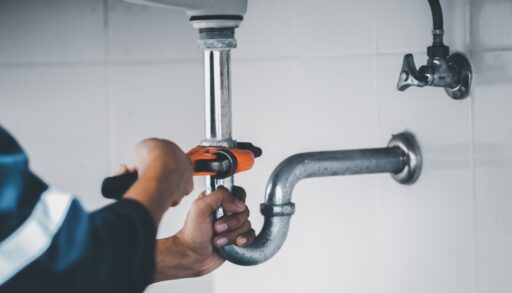 Person using a wrench to tighten sink pipes.