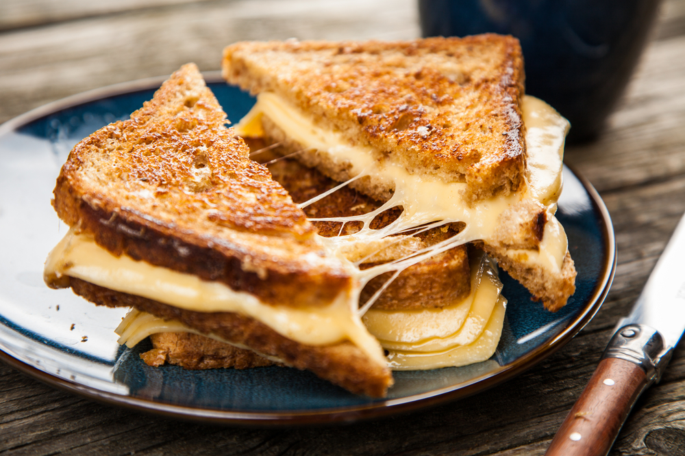 Grilled cheese sandwiches stacked on a blue plate.