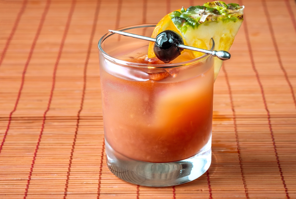 Bermudian rum swizzle cocktail on a red table.