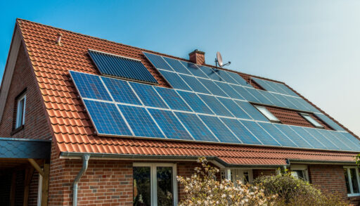 Blue solar panels on top of a red, shingled roof.