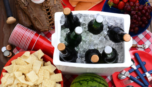 Overhead view of a cooler with beer bottles on a picnic table.
