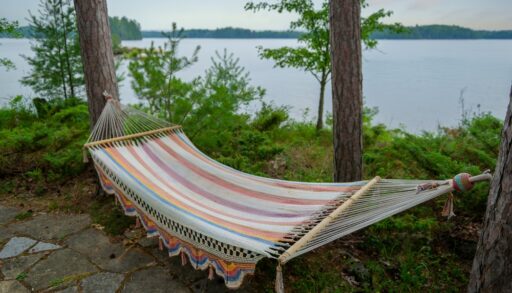 Colourful hammock hanging next to a lake.