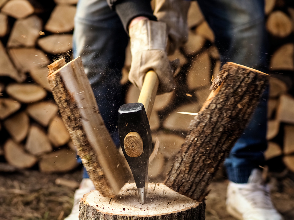 Person using an axe to split a piece of wood.