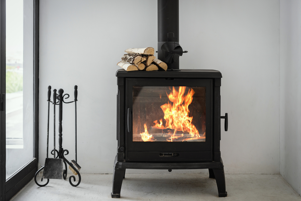 Black wood burning fireplace next to a window.