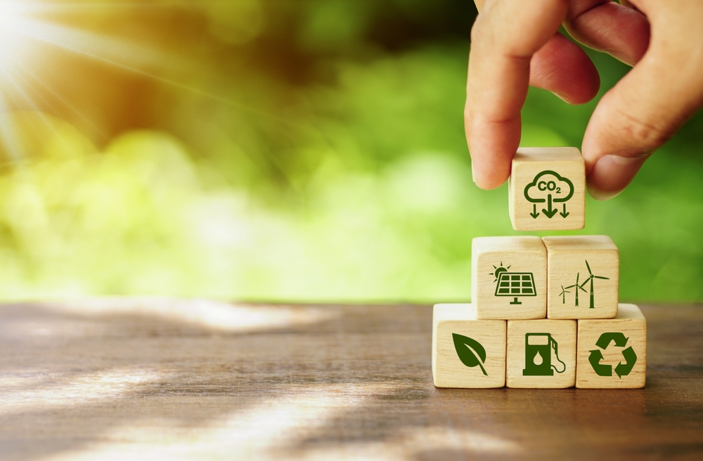 Person placing small building blocks with motifs related to reducing emissions, such as recycling or wind power.