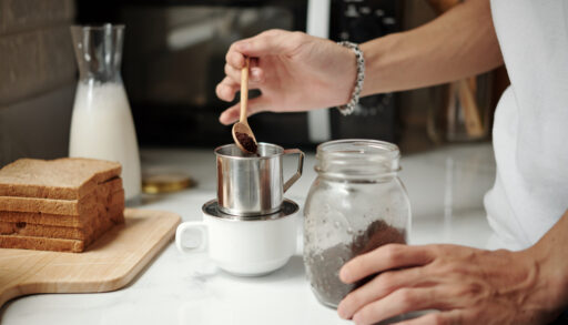 Man making a cup of coffee by putting coffee grounds into a cup.