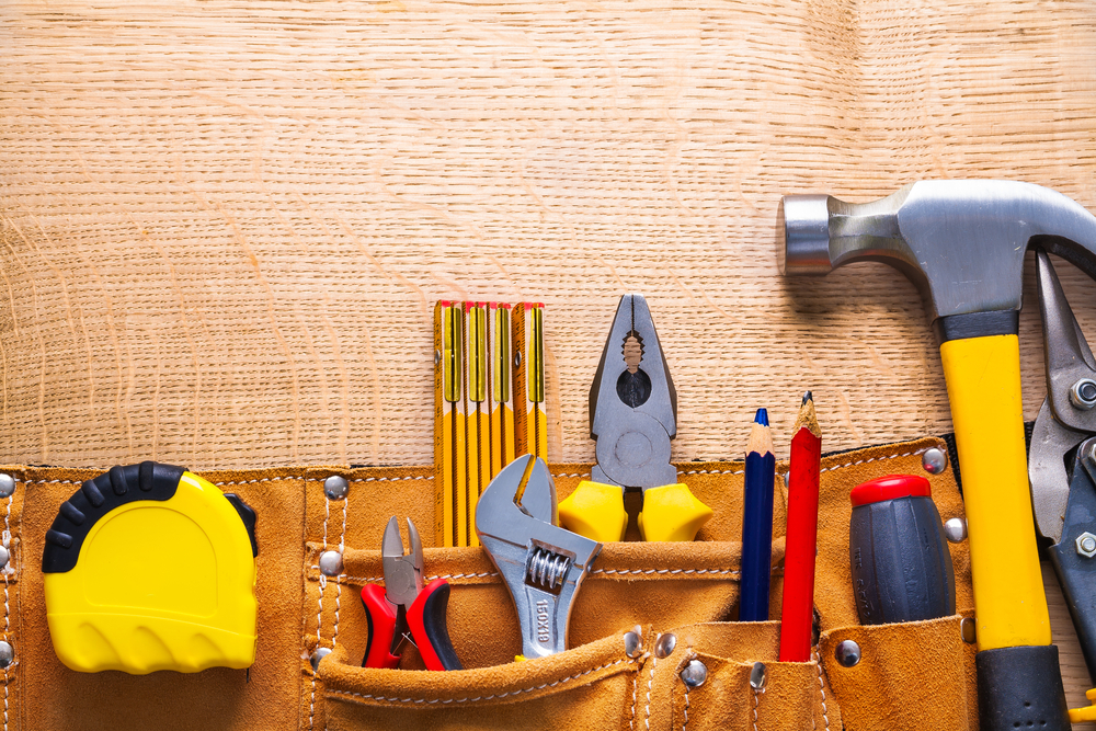 Tools sticking out of a toolbelt, including a tape measure, pliers and hammer.