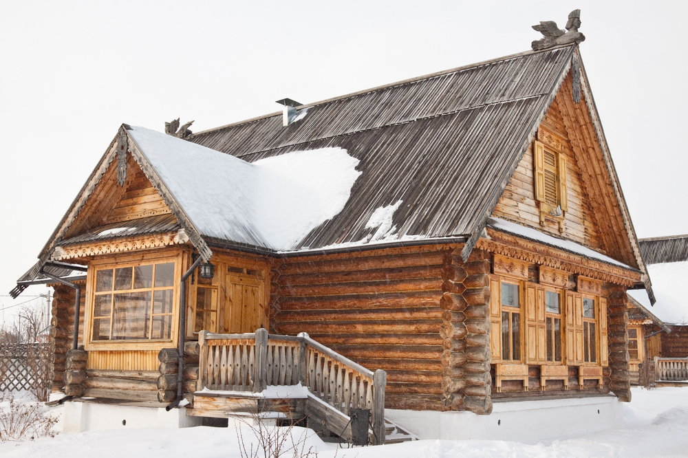 Wooden log cabin covered in snow.