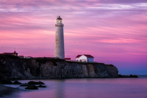 View of the Cap-des-Rosiers Lighthouse in Gaspe, Quebec at sunset.