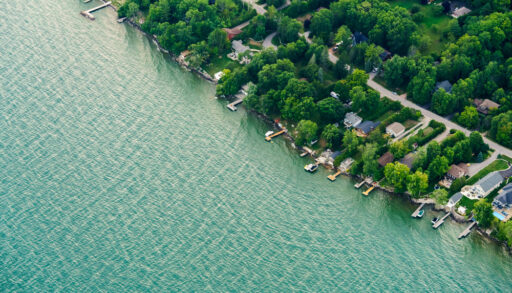 Aerial view of a blue Lake Ontario with houses along the shoreline.