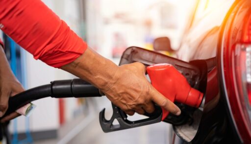 Close-up of a person using a red gas nozzle to fuel their car.