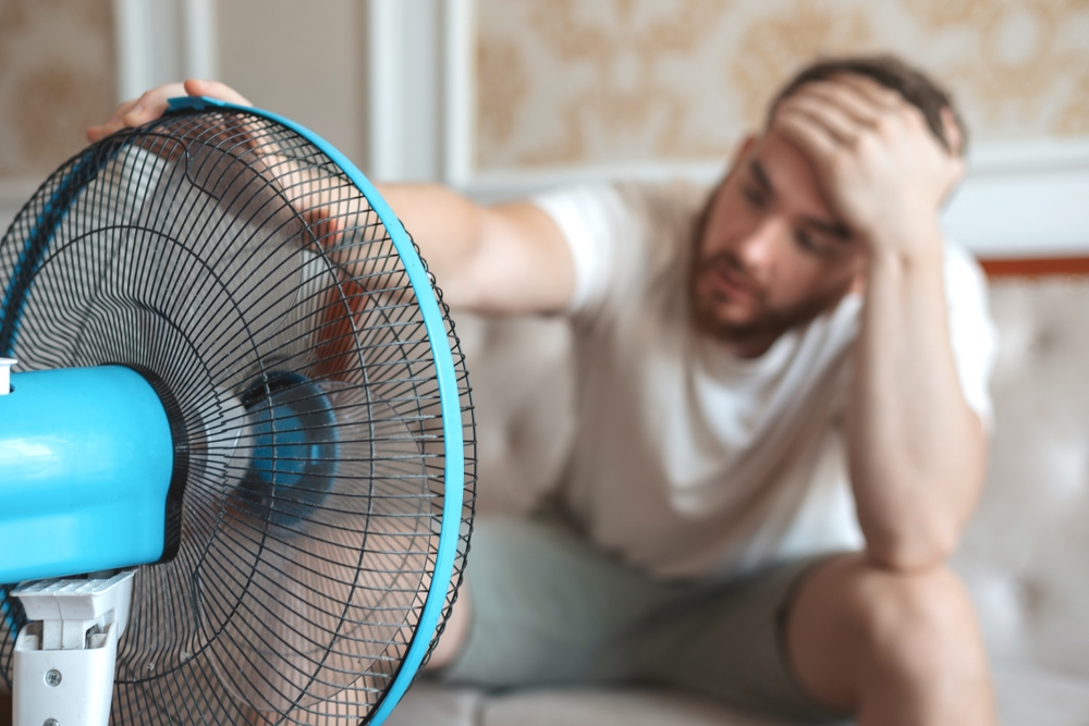 Young man using a fan to cool off.