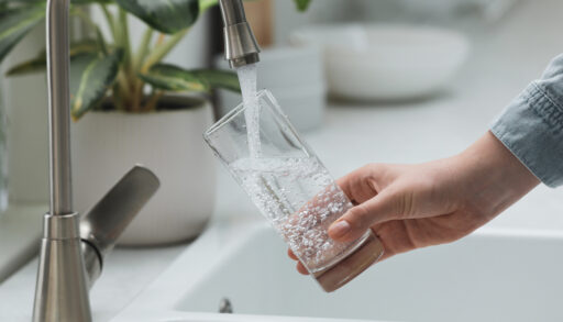Close-up of a person filling a glass with tap water.