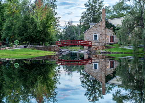 Red footbridge and stone house in Stewart Park, Perth, Ontario.