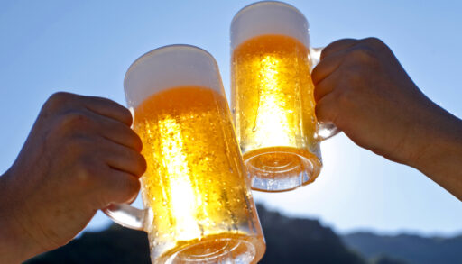 Close-up of people raising their beer glasses.