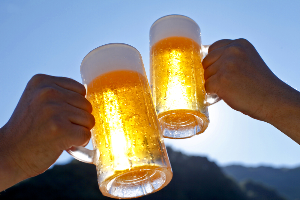 Close-up of people raising their beer glasses.