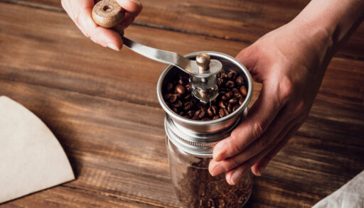 Close-up of a person using a coffee grinder to grind coffee beans.