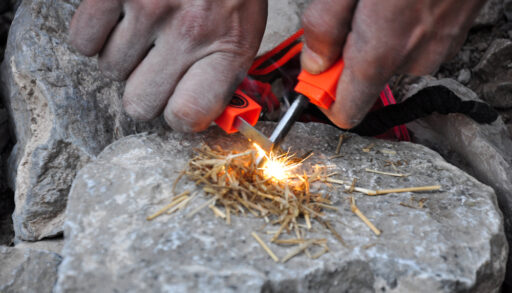 Close-up of a person using a fire starter to start a fire.