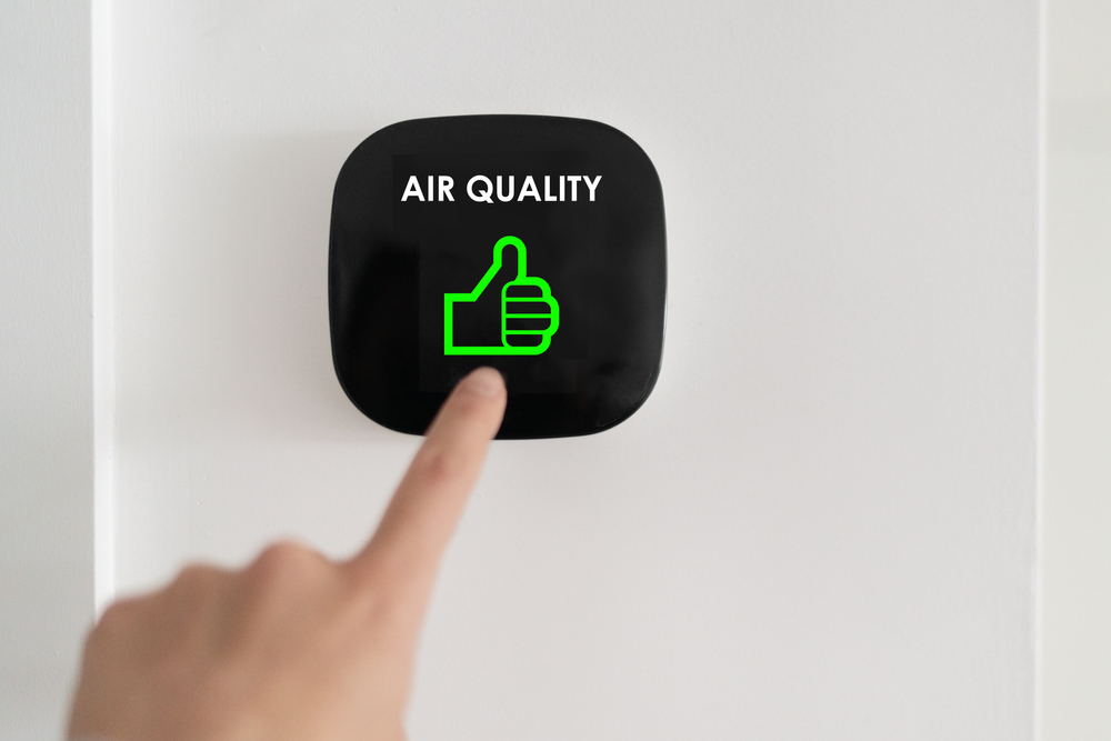Close-up of a person pressing an indoor air quality monitor.