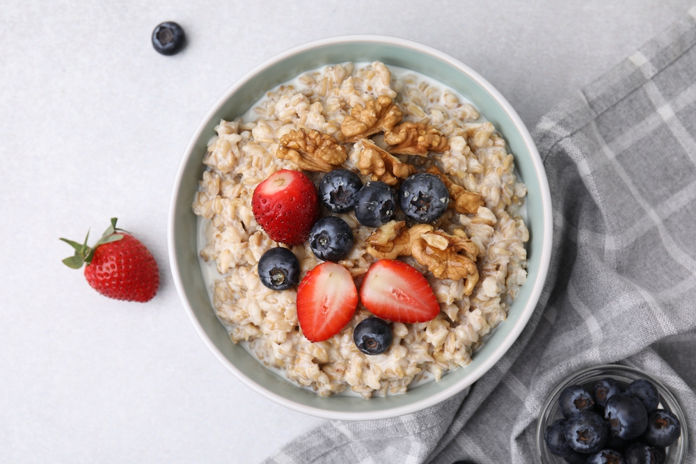 Overhead view of a bowl of oatmeal topped with blueberries, strawberries and walnuts.
