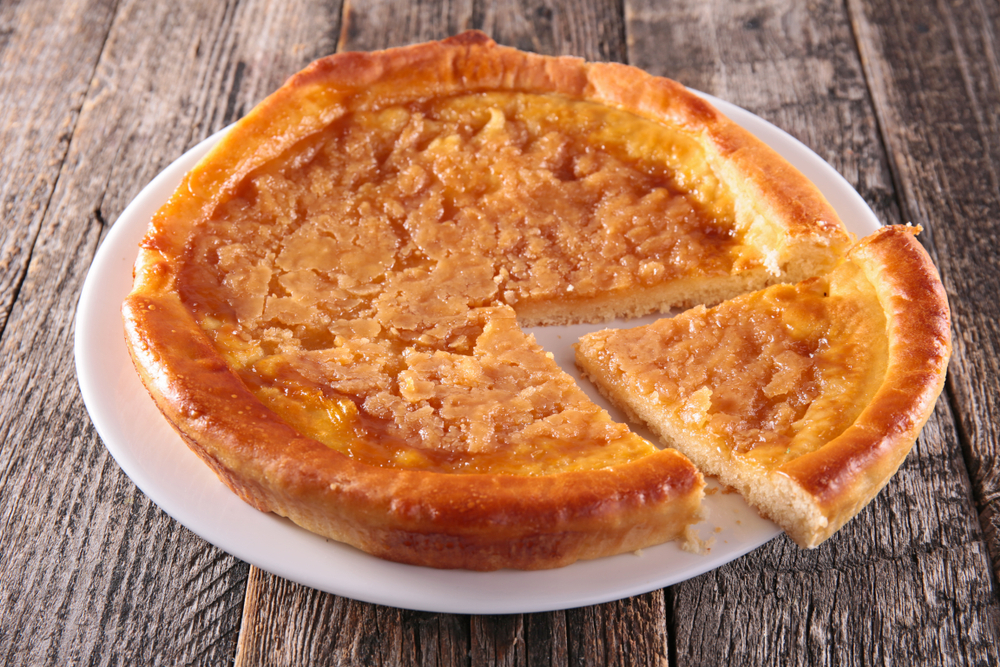 Close-up of a sugar tart on a white plate.