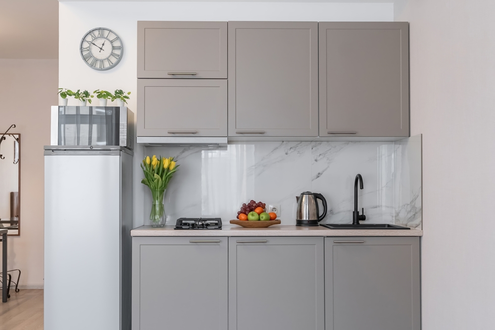 Small, modern kitchen with grey cabinets and small appliances.