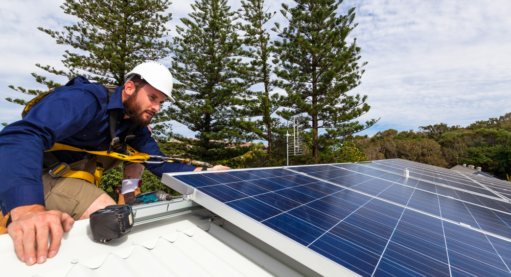 A solar panel technician installing solar panels on a house roof.