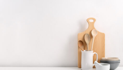 Wooden cutting board with a jar of kitchen utensils and bowls.