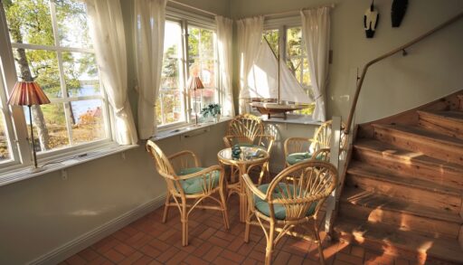 Small dining table with chairs in a cottage with sheer window coverings.