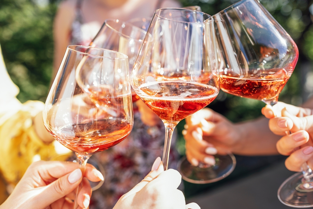 Group of people toasting with glasses of rose wine.