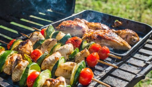 delicious grilled chicken meat shish kebob or kabob with vegetables on barbecue grill with smoke and flames