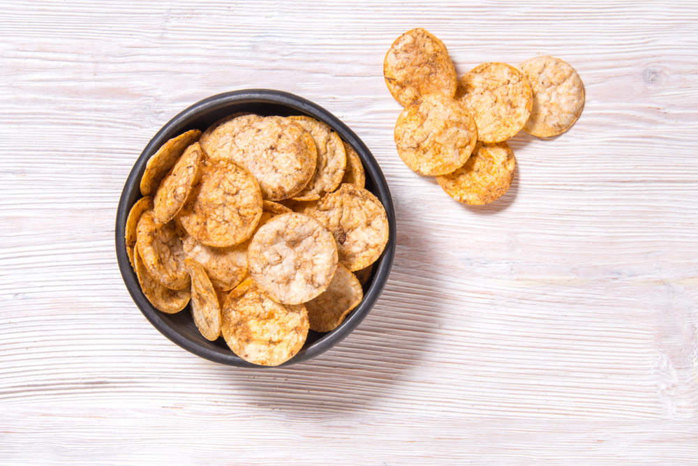 Overhead view of rice chips in a brown bowl.