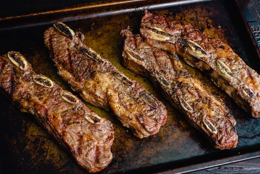 Grilled flanken ribs on a metal sheet pan.