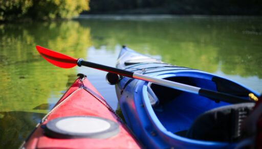 Close-up of the fronts of red and blue kayaks.