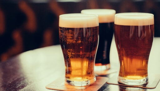 Close-up of three glasses of different amber-coloured beers on a table.
