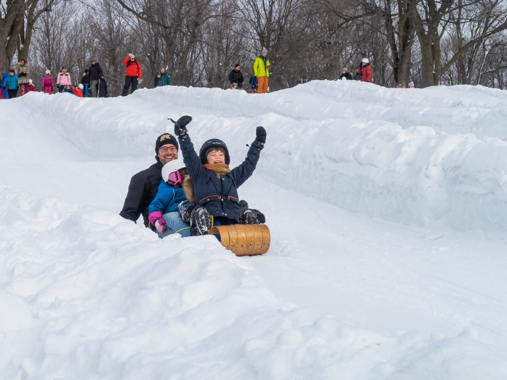 Family having fun sledding down a snowy hill.