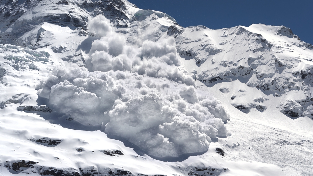 Avalanche of snow rumbling down a steep mountain.