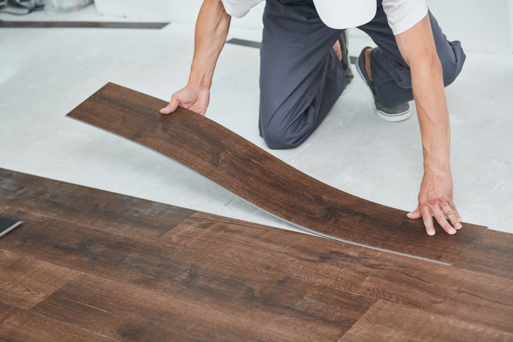 Person installing vinyl flooring made to look like wood floor.