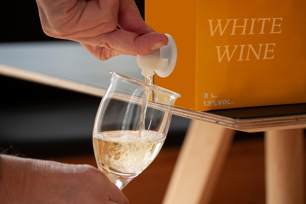 Close-up of someone pouring a glass of white wine from a wine box.
