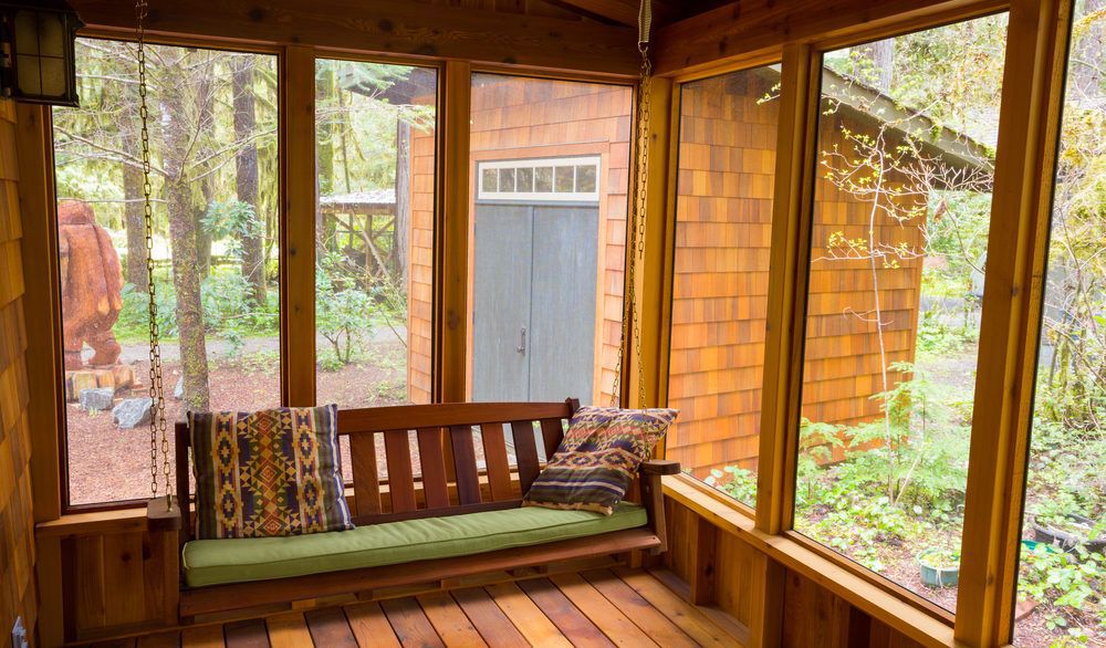 Wooden screened-in porch with a bench swing.