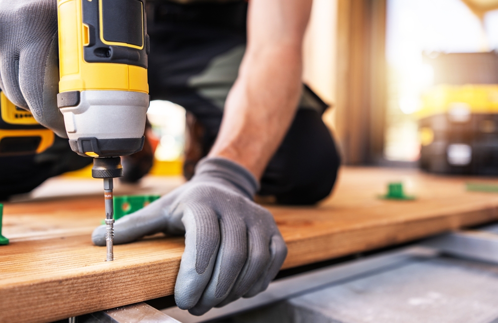 Person drilling a screw into a wooden board.
