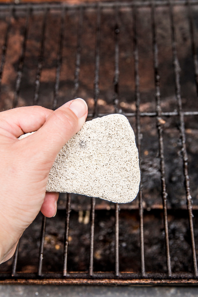 Natural pumice being used to clean a grill.