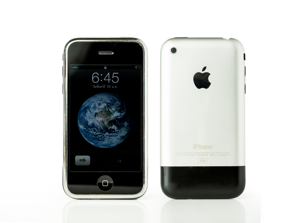 Old iPhone with a silver and black back and a world wallpaper lock screen.