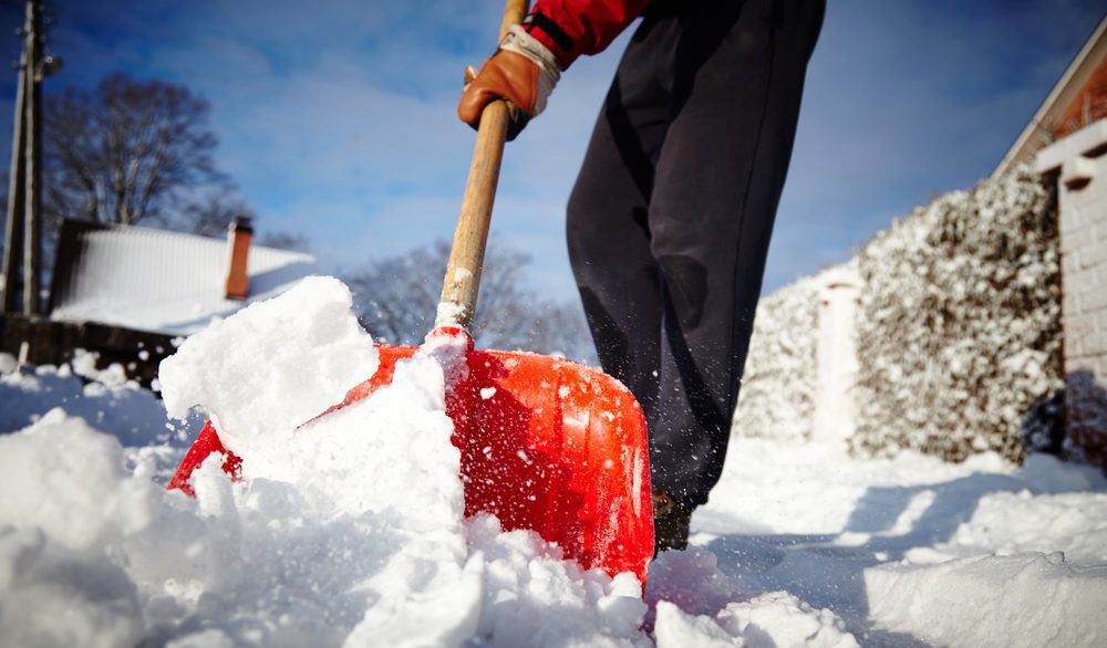 Person shovelling snow with a red shovel.
